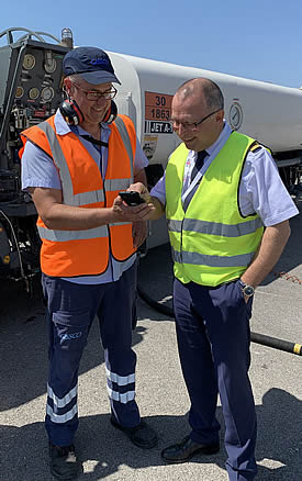 Pilot and airline representative (right) signs a delivery ticket on the handheld device on Air bp's safe2go fuelling app with the assistance of Grigoris Kazianis, GISSCO.